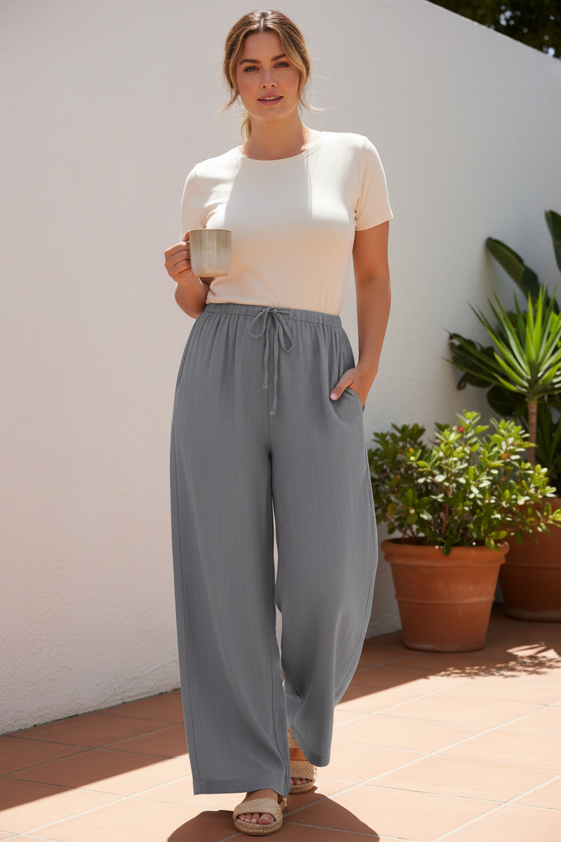 Mid-size woman wearing gray wide-leg linen drawstring pants outdoors.